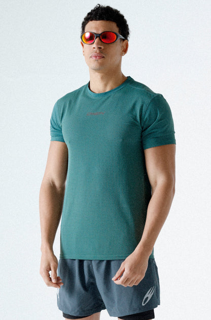 Man wearing a green athletic shirt and gray shorts on a white background